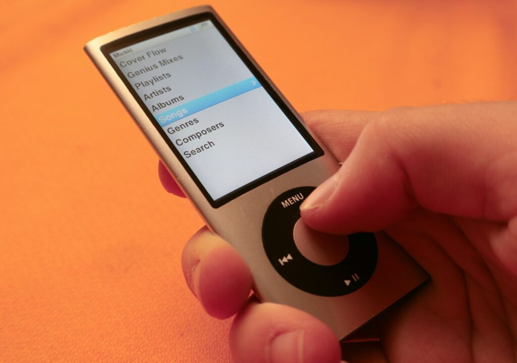 A hand holding an mp3 player on an orange surface
